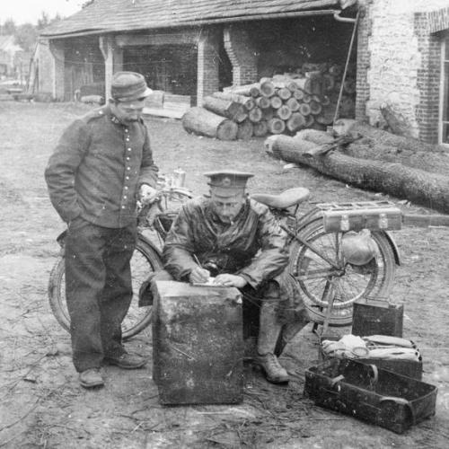 A British motorcycle dispatch rider takes a message in a Belgian village on 16 October 1914